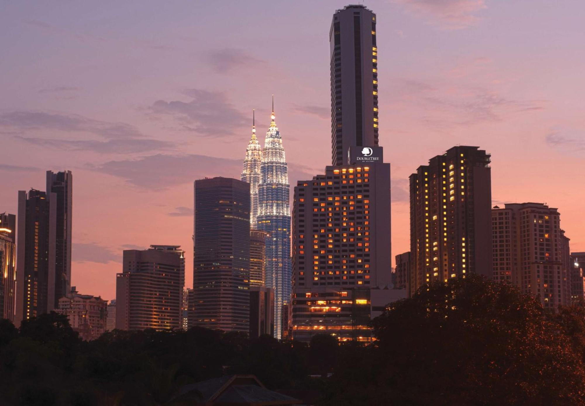 Doubletree By Hilton Kuala Lumpur Hotel Interior foto The photo showcases a city skyline at dusk, featuring tall buildings against a colorful sunset. Prominent in the image are two tower-like structures, which appear to be twin skyscrapers illuminated in a striking way, suggesting they might be iconic l